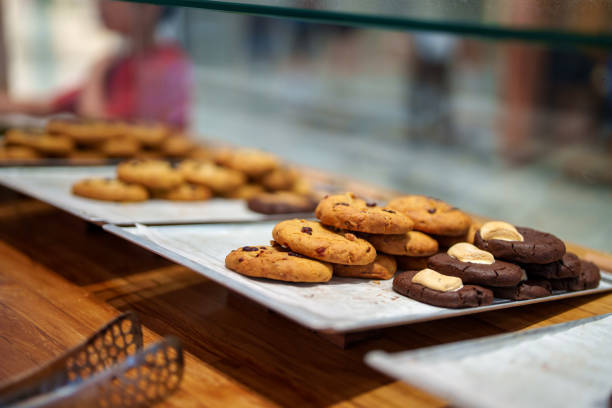 A close-up image of assorted cookies, including chocolate and nut varieties, arranged on trays in a bakery. The cookies showcase their fresh and homemade appeal, offering a delicious treat.