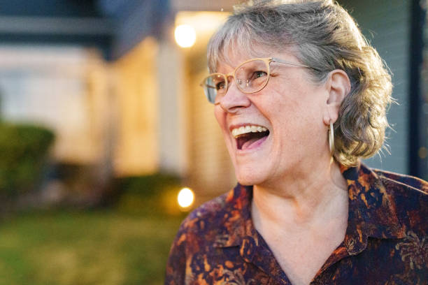 istock Joyful Mature Woman Laughing While Standing Outdoors at Twilight 2185108352