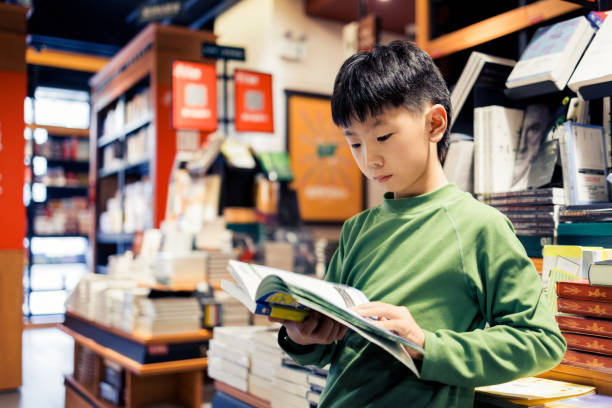 istock little asian boy is reading in a bookstore 2185110267
