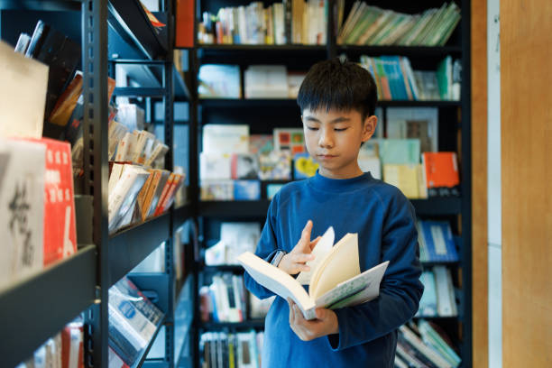 A asian primary school student is reading in a bookstore