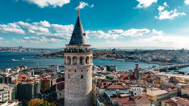 Drone captures a panoramic view of Istanbul’s Galata Tower surrounded by historic architecture, with the Bosphorus and city landmarks like Hagia Sophia in the background. aerial view of historic galata tower and vibrant cityscape of istanbul, iconic galata tower in istanbul, scenic views of the bosphorus and golden horn, panoramic view of istanbul’s famous galata tower, highlighting turkey’s unique cultural heritage