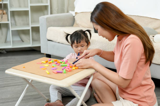 istock Asian single mother teaching young daughter colorful modeling clay art on small table in bright living room. Focus on creativity, child development, maternal love, and bonding moment. 2185116197