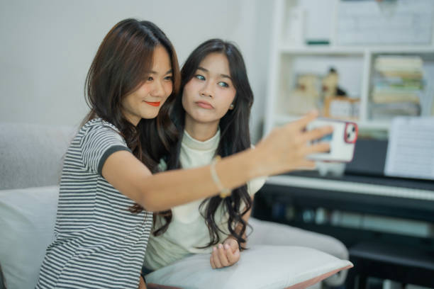 istock Two Young Asian Beautiful women two generation using smartphone selfie thireselve with close relationship in living room with fun and happiness. 2185116496
