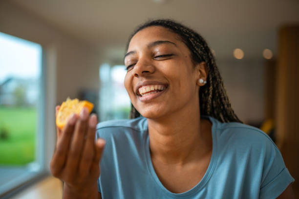 istock Cheerful Black Woman Enjoying Orange Fruit Indoors 2185124874