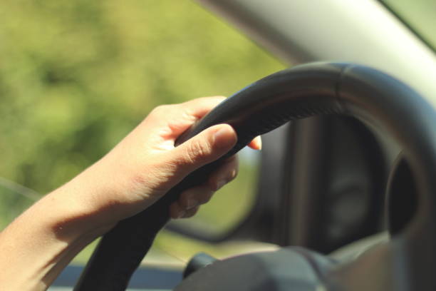istock Hand on Steering Wheel with Blurred Green Background 2185128027