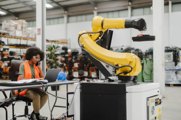 istock Female industrial robotics engineer programming and controlling robotic arm in factory 2185128032