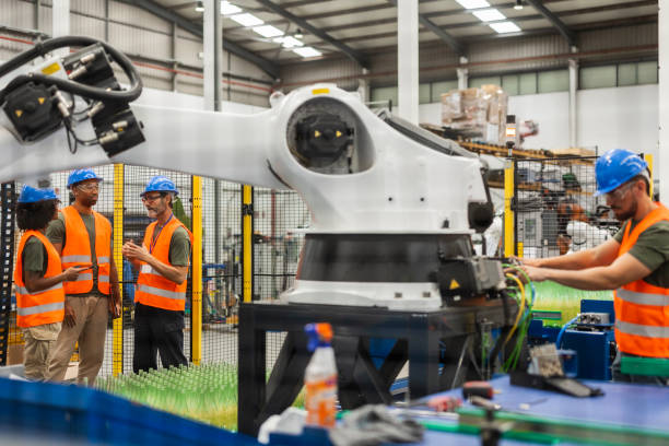 istock Engineers supervising and maintaining robotic arm in modern glass factory 2185128143