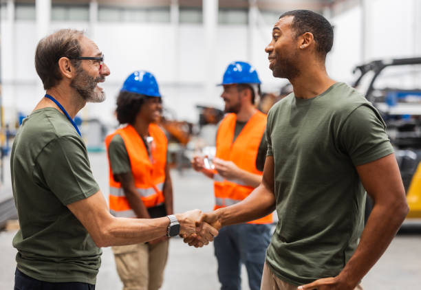 istock Engineers shaking hands in a modern industrial factory 2185128162