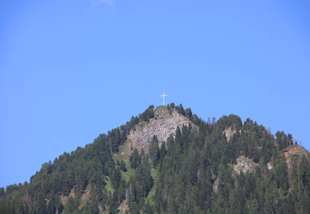 big white cross on the peak of mountain in summer