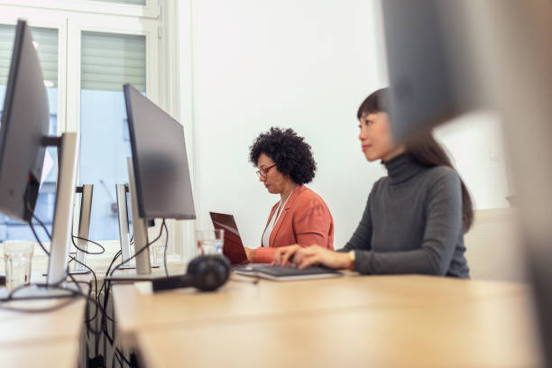istock Diverse female colleagues working together in a modern office, focused on coding 2185134120