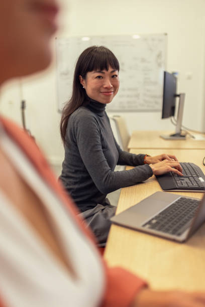 istock Japanese business woman using laptop and computer while working in office and looking directly at camera 2185134123