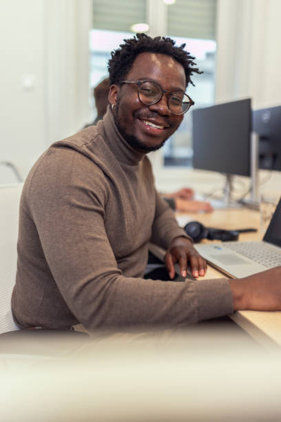 istock Smiling black business man looking directly at camera while working in modern office 2185134128