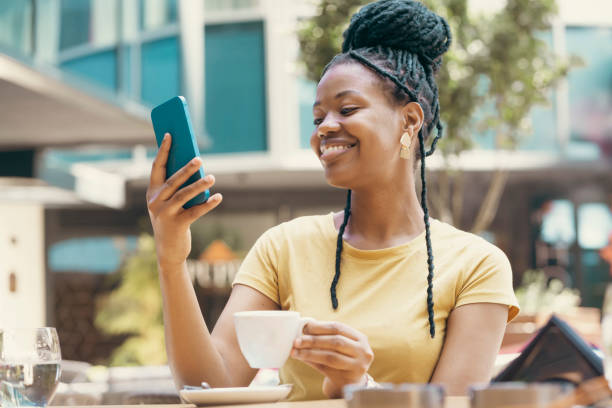 istock Young woman drinking coffee at cafe and using phone 2185134994