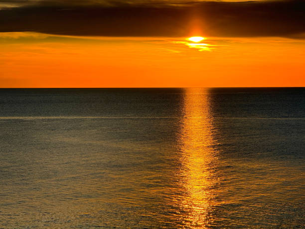Golden sunset sky and sea with glittering trace on water.