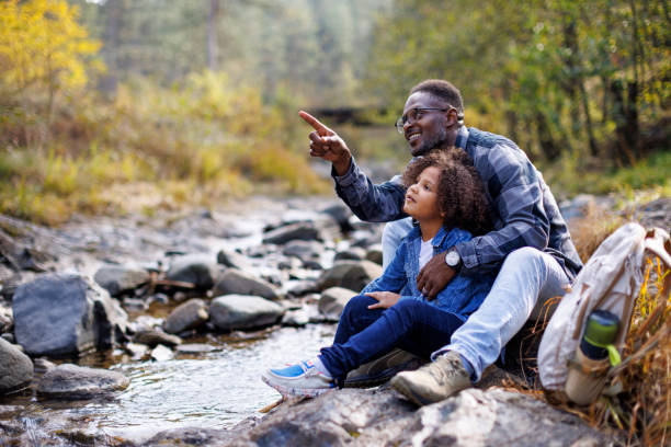 Father and child enjoying nature, relaxing by the stream