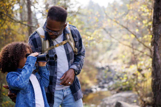 istock Father and daughter explore nature together with binoculars in the forest 2185137576