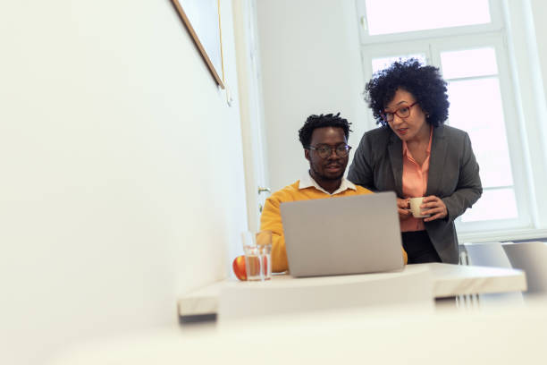 istock A black man shows a female colleague a project he made using a laptop 2185142312
