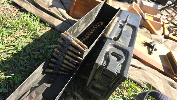 istock An open ammunition box reveals a belt of bullets resting inside, set on a grassy surface with nearby military equipment, suggesting a historical or reenactment scene. 2185143797