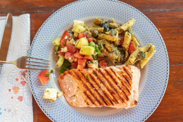 Plate with grilled salmon served with vegetables, salad on wooden table. Directly above.