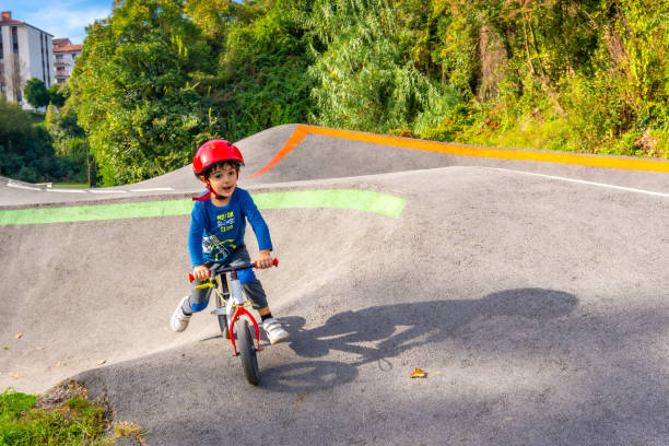 A young boy is riding a bike on a dirt road. The boy is wearing a helmet and a blue shirt