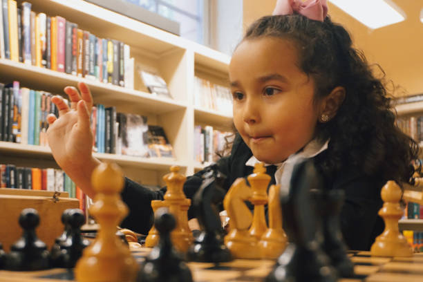 A girl plays chess in a library