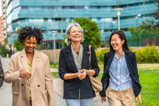 Multi-ethnic businesswomen talking relaxed while walking along a urban park