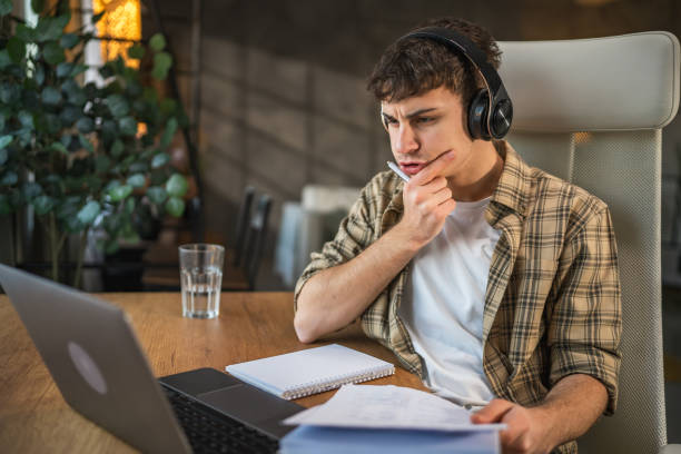 istock young man with headphones write notes in notebook watch video course 2185158265
