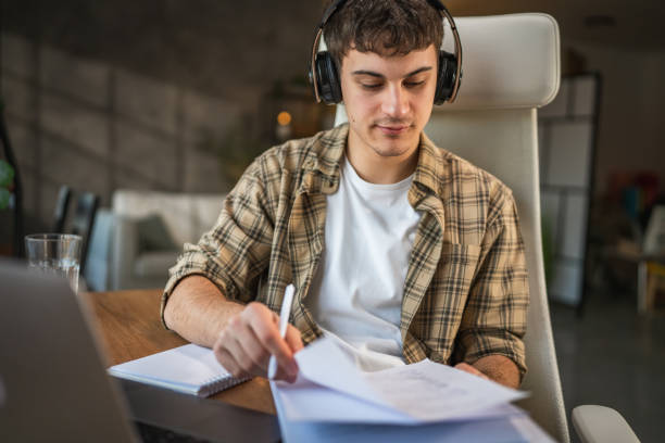 istock young man with headphones write notes in notebook watch video course 2185158316