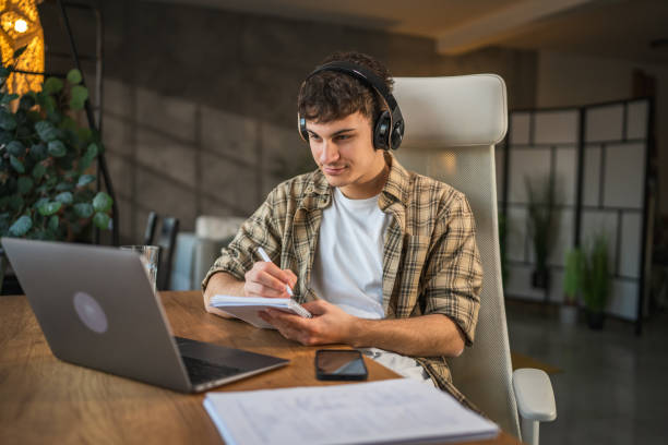 istock young man with headphones write notes in notebook watch video course 2185158491