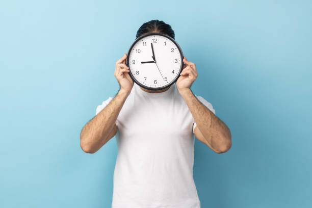 istock Man holding wall clock hiding her face, time management, schedule and meeting appointment. 2185161431