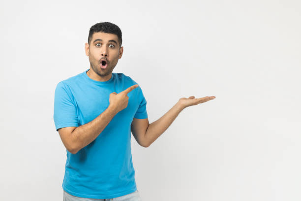 istock Amazed excited surprised astonished man presenting advertisement area on his palm, mockup. 2185161495
