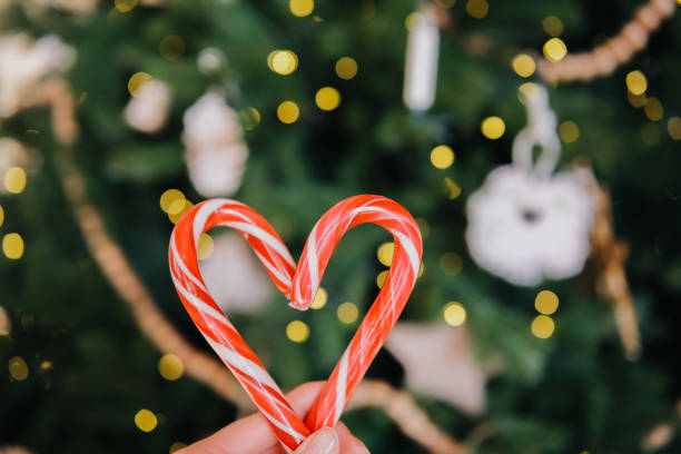 istock Heart-shaped candy cane held against a beautifully decorated Christmas tree 2185163178