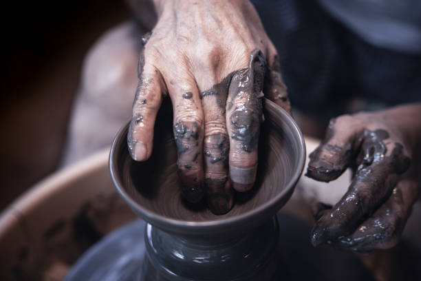 Close-up of potter's hands working with clay on a spinning wheel, crafting a pottery piece with skill and precision
