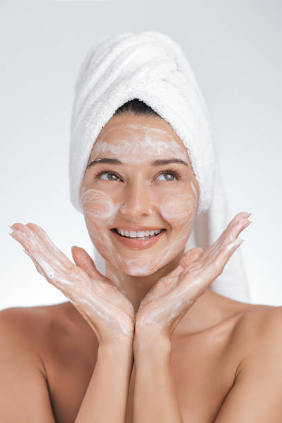 istock Cheerful Woman Cleansing Face with Foaming Cleanser in Beauty Routine 2185169119