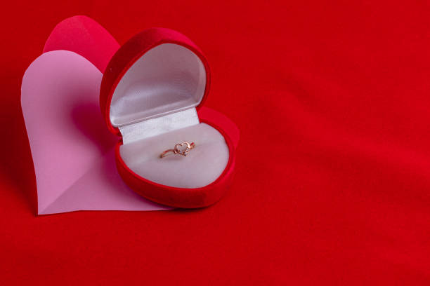 istock heart shaped ring with diamonds on a hand cut paper heart on a red background 2185178017