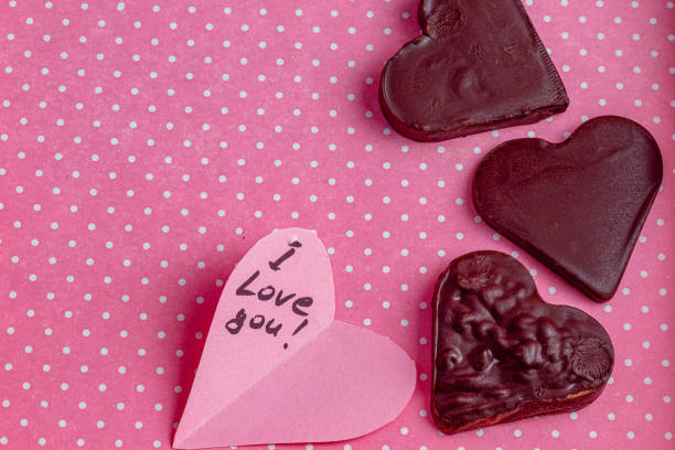 Chocolate hearts with a note I love you on a pink dotted background High quality photo.