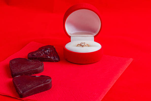 A chocolate heart on a red napkin with a ring in a box on a red background High quality photo.