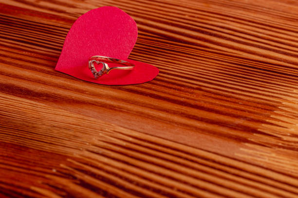 Wedding ring on a paper heart on a wooden board High quality photo.