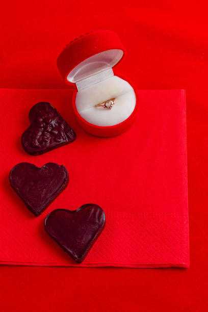 istock Chocolate hearts on a red napkin with a ring in a box on a top view 2185181132