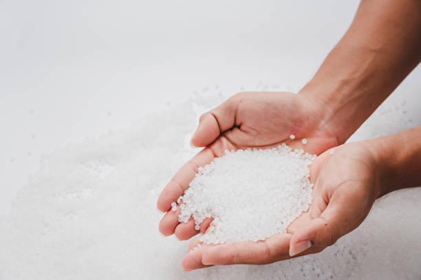 istock Hands hold clear white plastic pellets, raw materials for various manufacturing processes. These pellets are widely used in industries to produce products like packaging, bottles, and equipment parts. The white background highlights the pellets, making th 2185182486