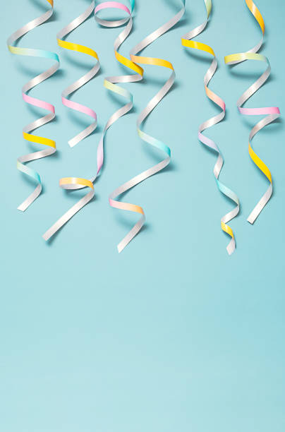 istock Colorful party streamers hanging down against pastel blue background. 2185183000
