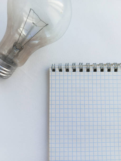 istock An incandescent lamp and a notebook are lying on a white table. Monthly electricity bill. Rising utility prices. Energy saving. 2185183404