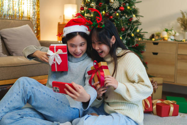 istock Two friends wearing festive headbands, sitting by the Christmas tree, joyfully video calling with loved ones during the holiday season 2185186201
