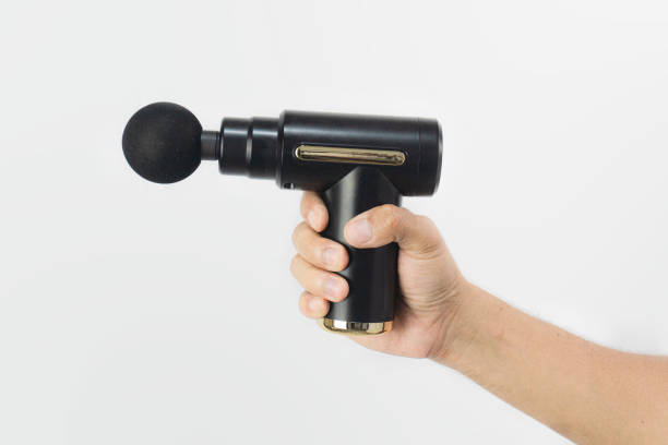 istock hand holding a black massage gun in white isolated background. Massage gun for healthy lifestyle. 2185192425