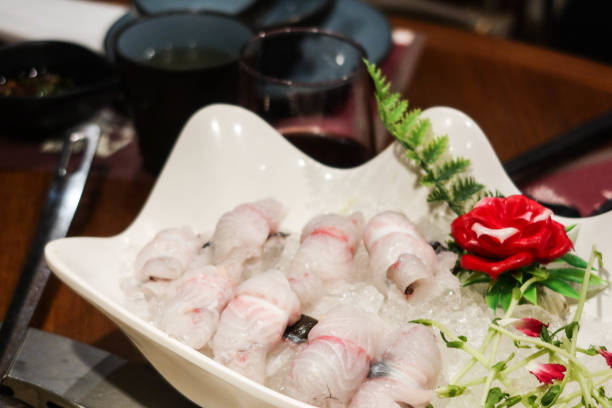 istock Chinese raw uncooked eel fish in sliced roll with flower and leaf on the side as decoration in a white plate. The ingredient is ready for hot pot. 2185194295