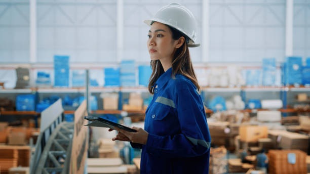 istock Female engineer in a hardhat and uniform supervising warehouse operations with precision. Managing logistics and production in a modern industrial environment. 2185195514