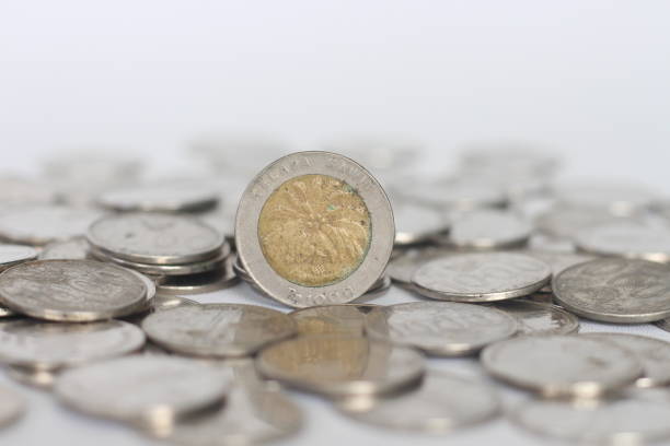 A close-up, high-angle shot of a Rwandan 100 Franc coin resting on a bright yellow surface. The sunlight casts interesting, organic shadows on the background, adding a unique texture and visual appeal. The coin is in clear focus, with the Rwandan crest and the words \