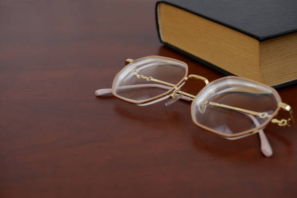 istock Eyeglasses on book on white wooden table. 2185197352