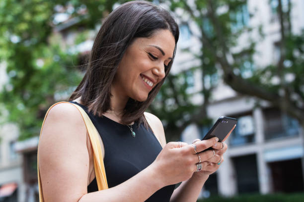 istock Smiling woman messaging on smartphone in city 2185197645