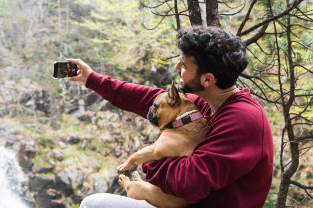 istock Smiling traveling man taking selfie with dog in forest 2185206426